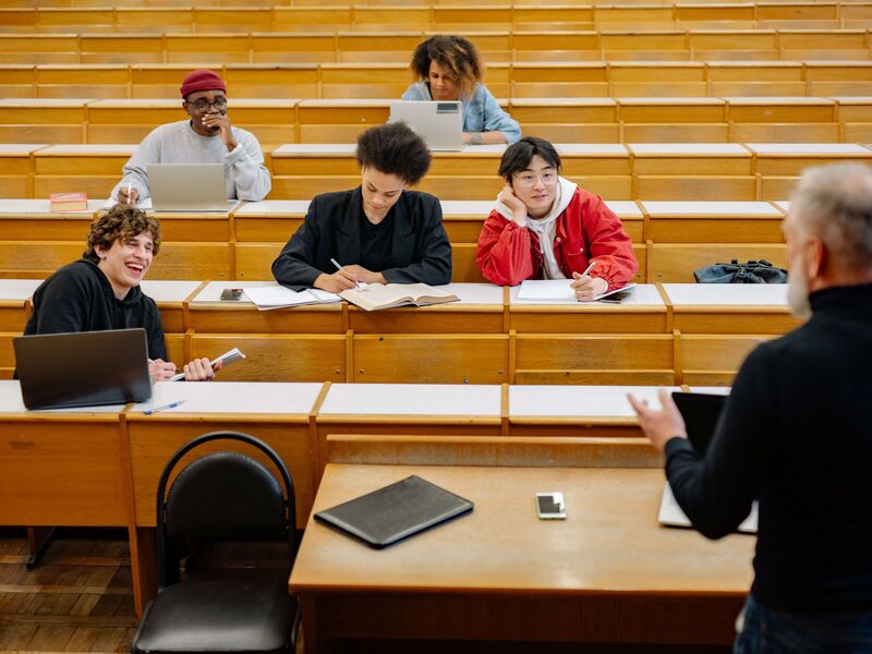 Studenten in einem Hörsaal hören aufmerksam einem Dozenten zu und bereiten sich auf die Approbation vor.