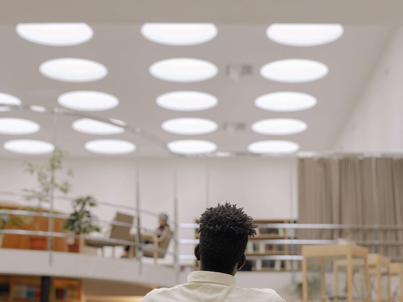 Ein Mann sitzt in einer modernen, hell erleuchteten Bibliothek und studiert an einem Tisch.