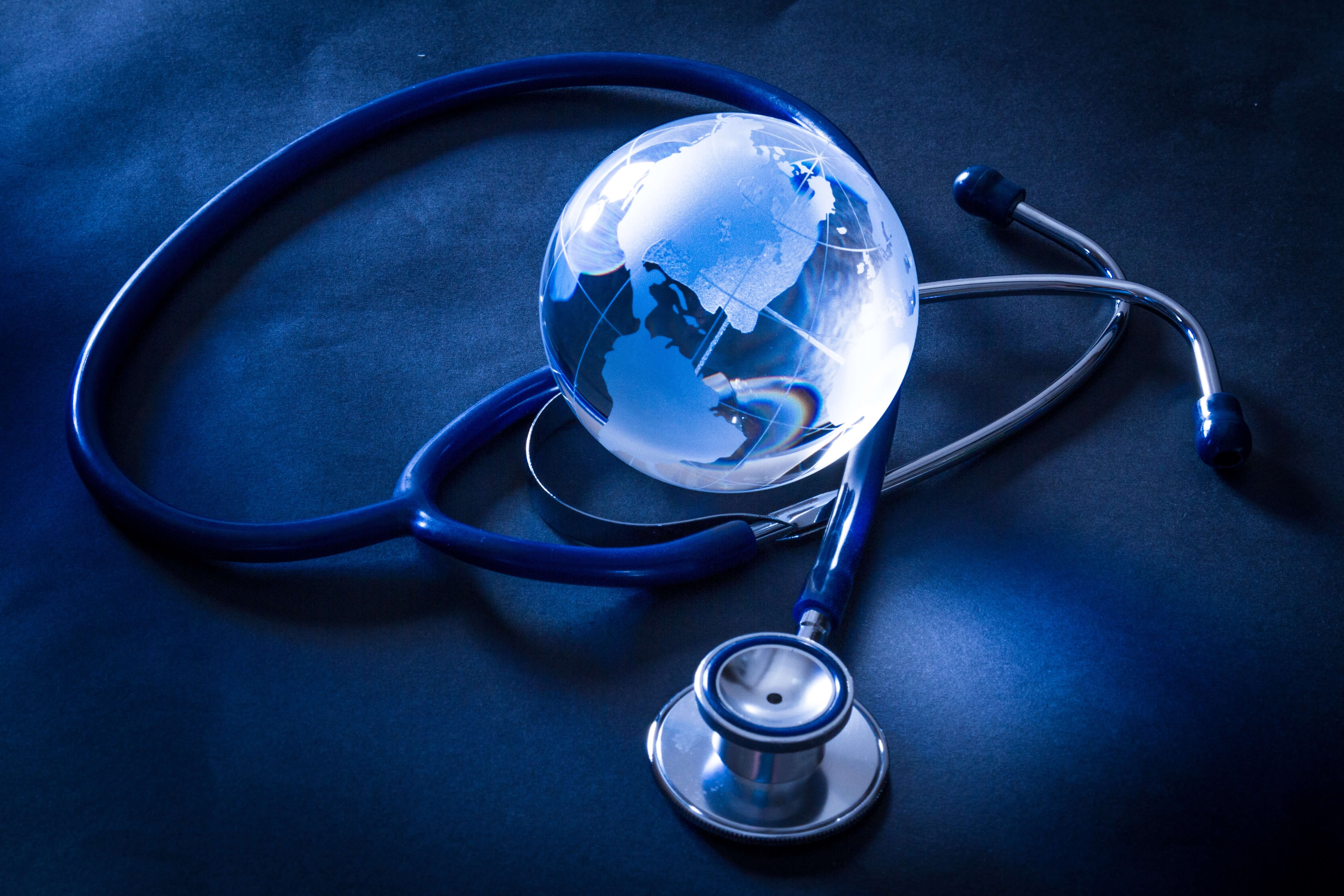 Ein Stethoskop umschlingt eine transparente Erdkugel, symbolisch für die globale Gesundheit und Medizin im Klimawandel.
